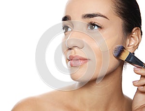 Young woman applying foundation on her face