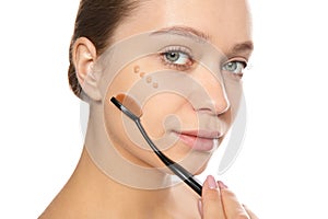 Young woman applying foundation on her face