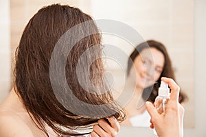 Young woman applying hair spray