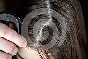 Young woman applying hair spray cream.