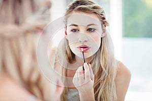 Young woman applying lip gloss