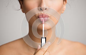 Young woman applying lip gloss on her lips