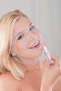 Young woman applying lip stick