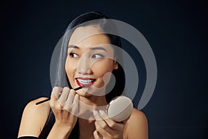 Young woman applying lipstick with an applicator