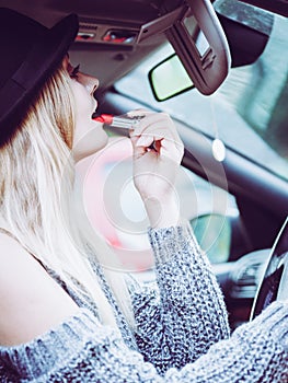 Young woman applying lipstick in car