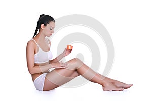 Young woman applying lotion on her body
