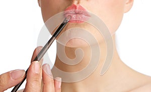 Young woman applying make up on lips