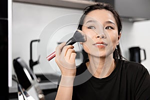 Young Woman Applying Makeup with Brush Indoors