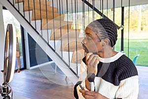 Young Woman Applying Makeup with a Brush in a Modern Home