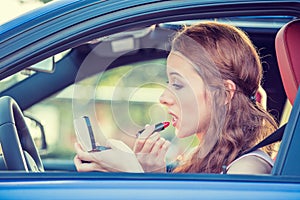 Young woman applying makeup while driving car