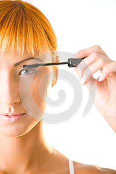 Young woman applying mascara