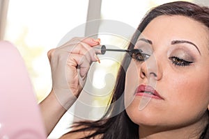 Young woman applying mascara on her eyelashes