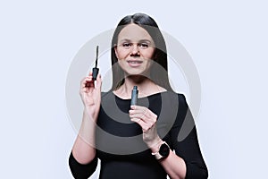 Young woman applying mascara on her eyelashes, on white background