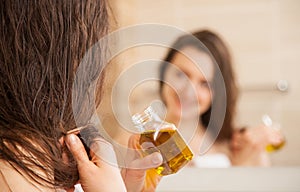 Mladá žena použitie olej na vlasy tipy 