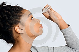 Young woman applying ophthalmology eyedropper, glaucoma eye prevention