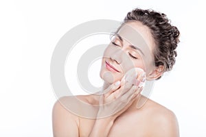 Young woman applying powder to her face.