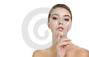 Young woman applying several color samples of facial foundation cream at her face