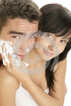 Young woman applying shaving foam on mans face