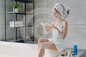 Female apply skincare anticellulite lotion doing body care routine in bathroom. Spa cosmetics ad photo