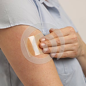 YOUNG WOMAN APPLYING TRANSPARENT NICOTINE PATCH TO ARM