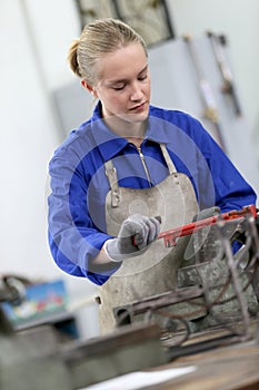 Young woman apprentice learning ironworks photo