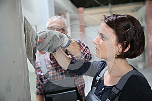 Young woman apprentice in plastery with professor