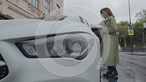 A young woman approaches the car and opens it using a mobile phone. Car rent.