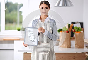 Young woman in the apron is cooking in the kitchen