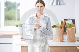 Young woman in the apron is cooking in the kitchen
