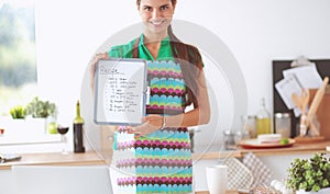 Young woman in the apron is cooking in the kitchen