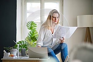 Young woman architect sitting at the desk indoors in home office, working.