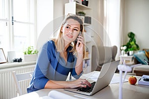 Young woman architect sitting at the desk indoors in home office, working.