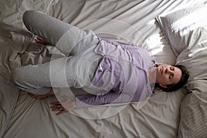 Young woman in ardha chakrasana yoga pose on bed in the morning