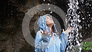 Young woman arms outstretched behind spectacular waterfall. Young woman outstretching arms by majestic waterfall.