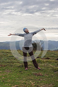Young woman with arms outstretched on the top of mountain. Success and winning concept. Active sport background.