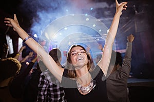 Young woman with arms raised enjoying at nightclub