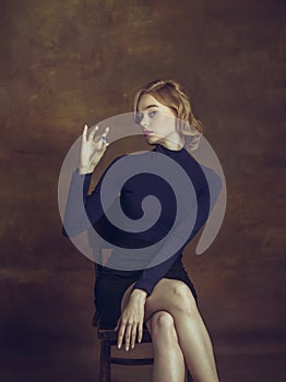 Young woman in art action isolated on brown background. Retro style, comparison of eras concept.
