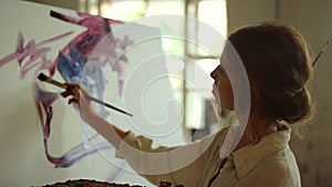 Young woman artist drawing in studio. Skilled painter using palette indoors.