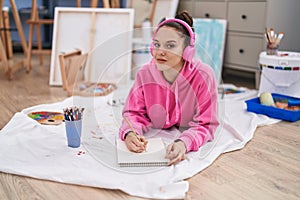 Young woman artist listening to music drawing on notebook at art studio