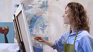 Young woman artist painting at art studio