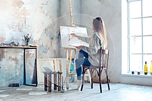 Young woman artist painting at home creative painting back view