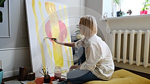 Young woman artist is painting at home in a creative studio setting.