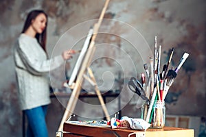 Young woman artist painting at home creative tools close-up