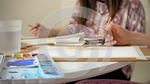 Young woman artist painting at home studio creative tools close-up