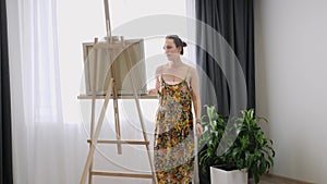 Young woman artist painting picture on canvas in studio. Talented female working on abstract painting using paint brush