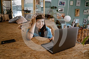 Young woman artist using laptop while resting in hammock at her studio