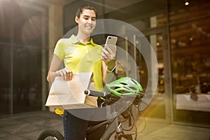 Young woman as a courier delivering package using gadgets
