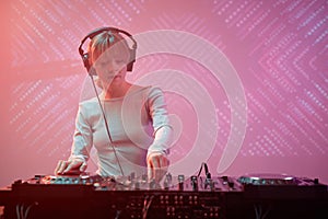 Young woman as DJ wearing headphones in nightclub