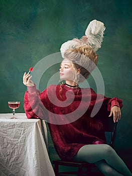 Young woman as Marie Antoinette on dark background. Retro style, comparison of eras concept. photo