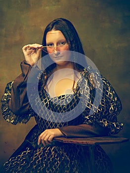 Young woman as Mona Lisa on dark background. Retro style, comparison of eras concept.